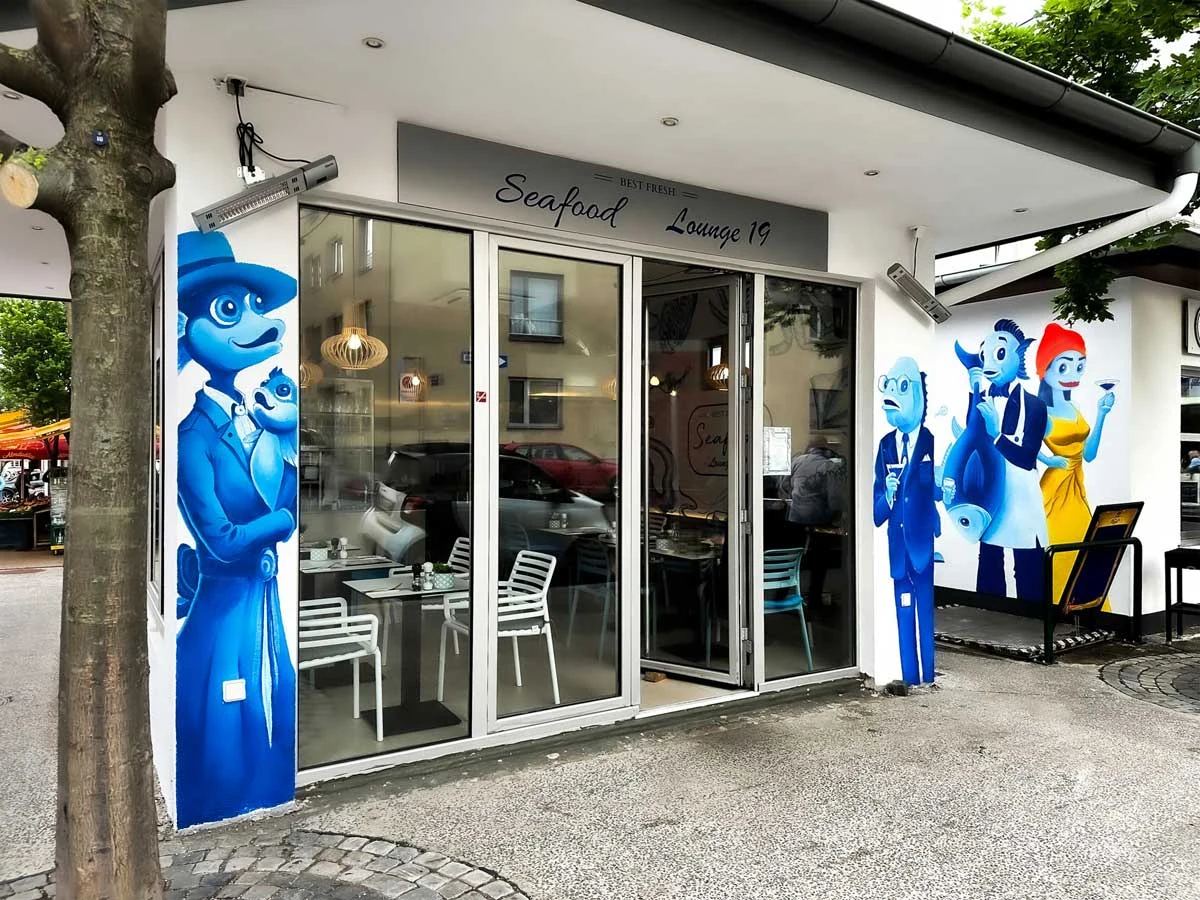 Seafood Lounge 19 mit strategischer Wandmalerei und Fischfiguren an der Fassade
